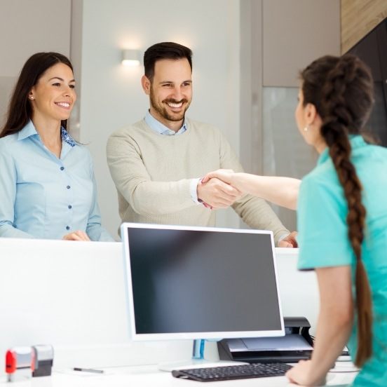 Man and woman checking in at dental office reception desk