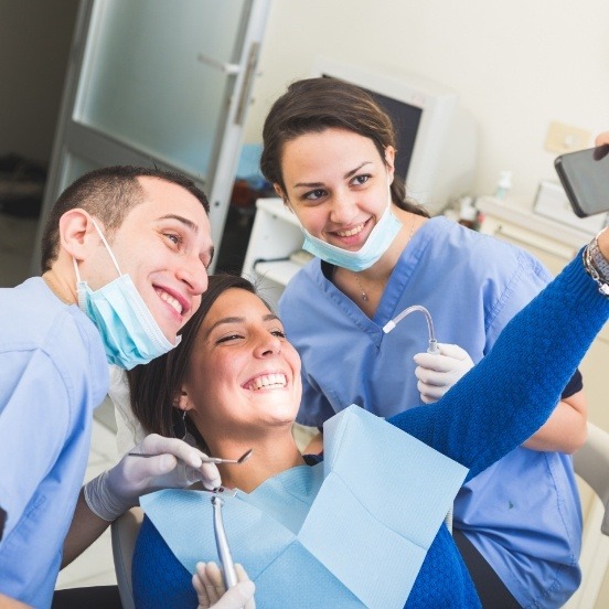 Dentist dental patient and team member taking picture together