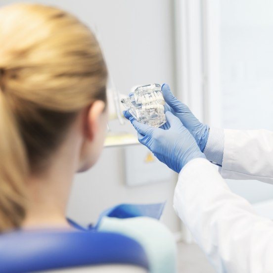 Dentist and patient looking at smile model during dental checkup and teeth cleaning visit