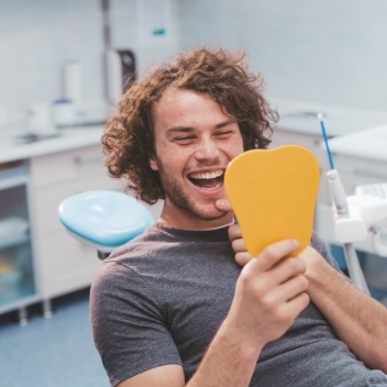 Man smiling and looking in mirror during dental visit