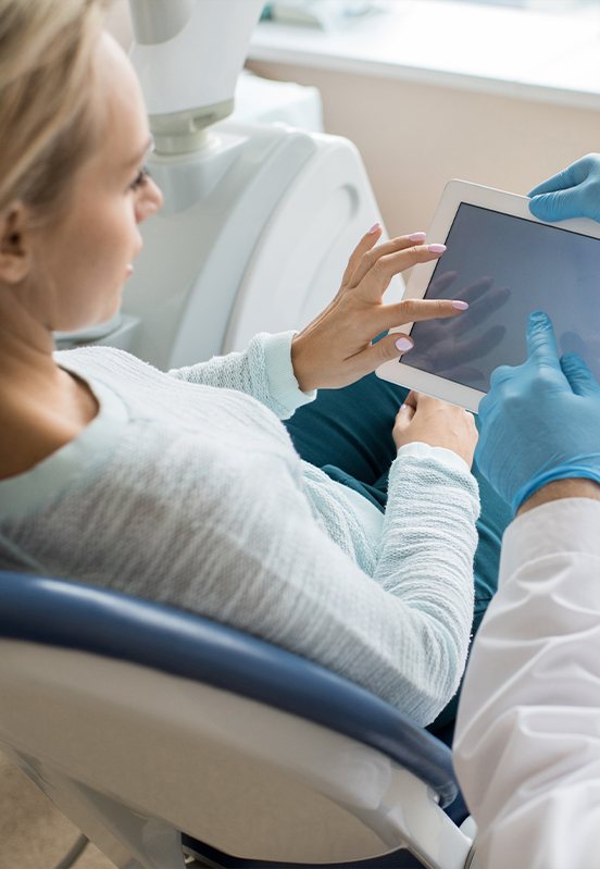 Dentist and patient looking at tablet computer