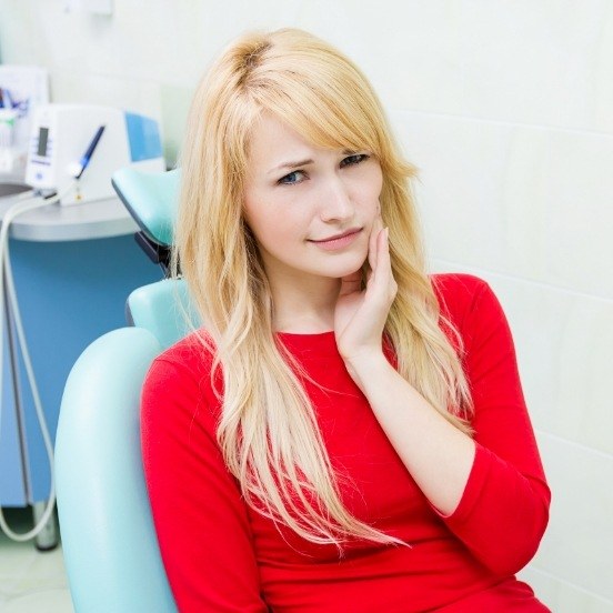 Woman holding cheek in pain before wisdom tooth extractions